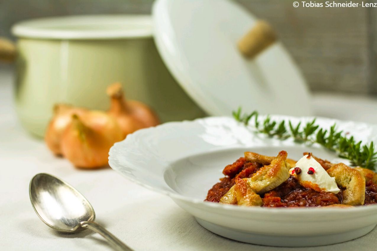 Hendlgulasch auf Teller vor einem Topf