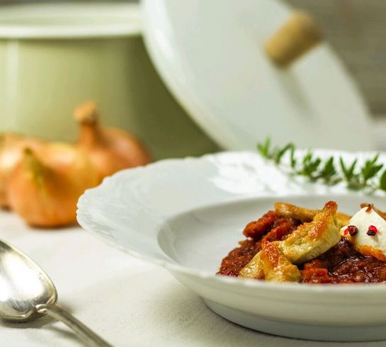 Hendlgulasch auf Teller vor einem Topf