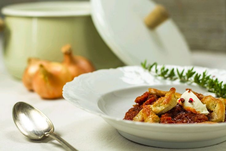 Hendlgulasch auf Teller vor einem Topf