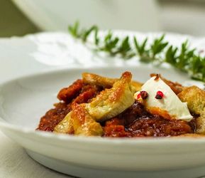 Hendlgulasch auf Teller vor einem Topf